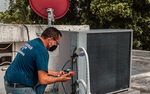 A technician with gauges servicing an outdoor unit.