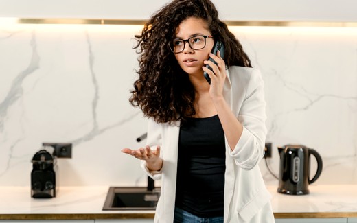 A woman on her phone in a kitchen at home.